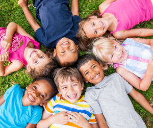 Kids smiling in a circle in the summer.